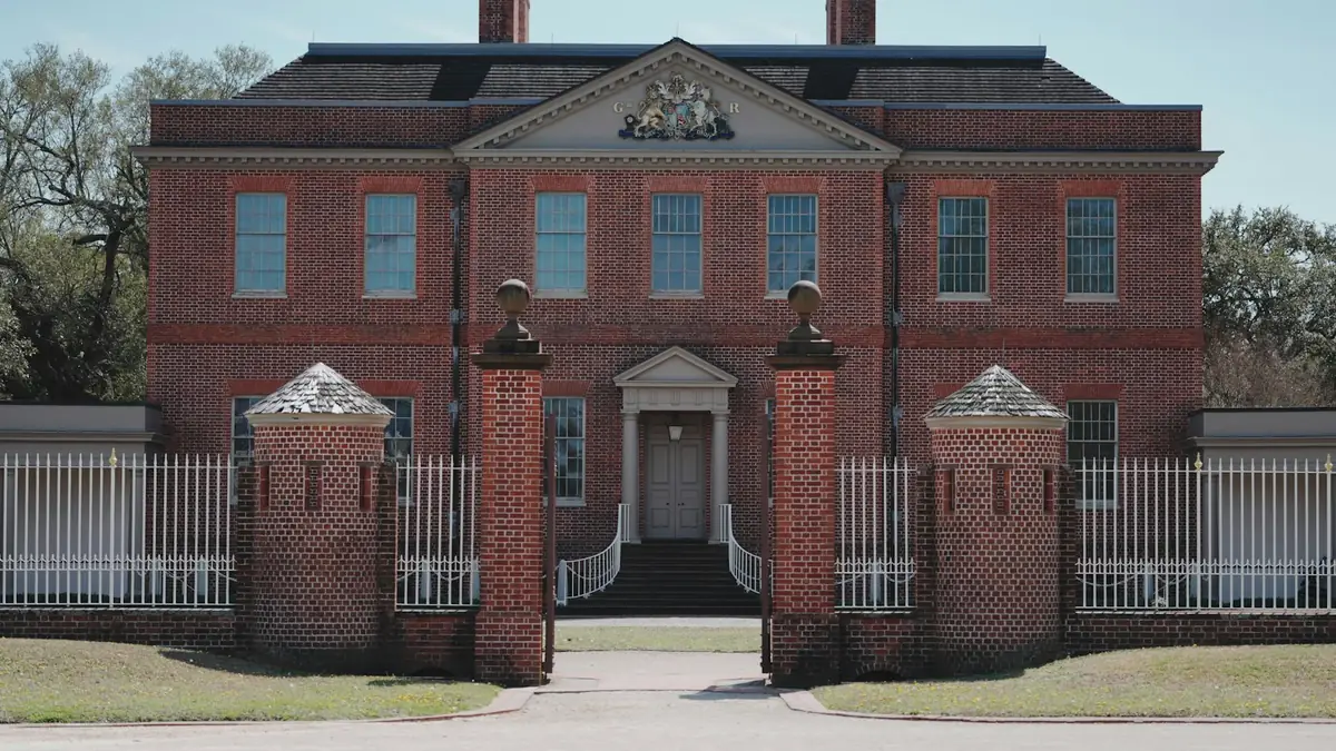 A two-story red brick Georgian house with a white fence and brick gate piers - Leak Detection in Petersburg